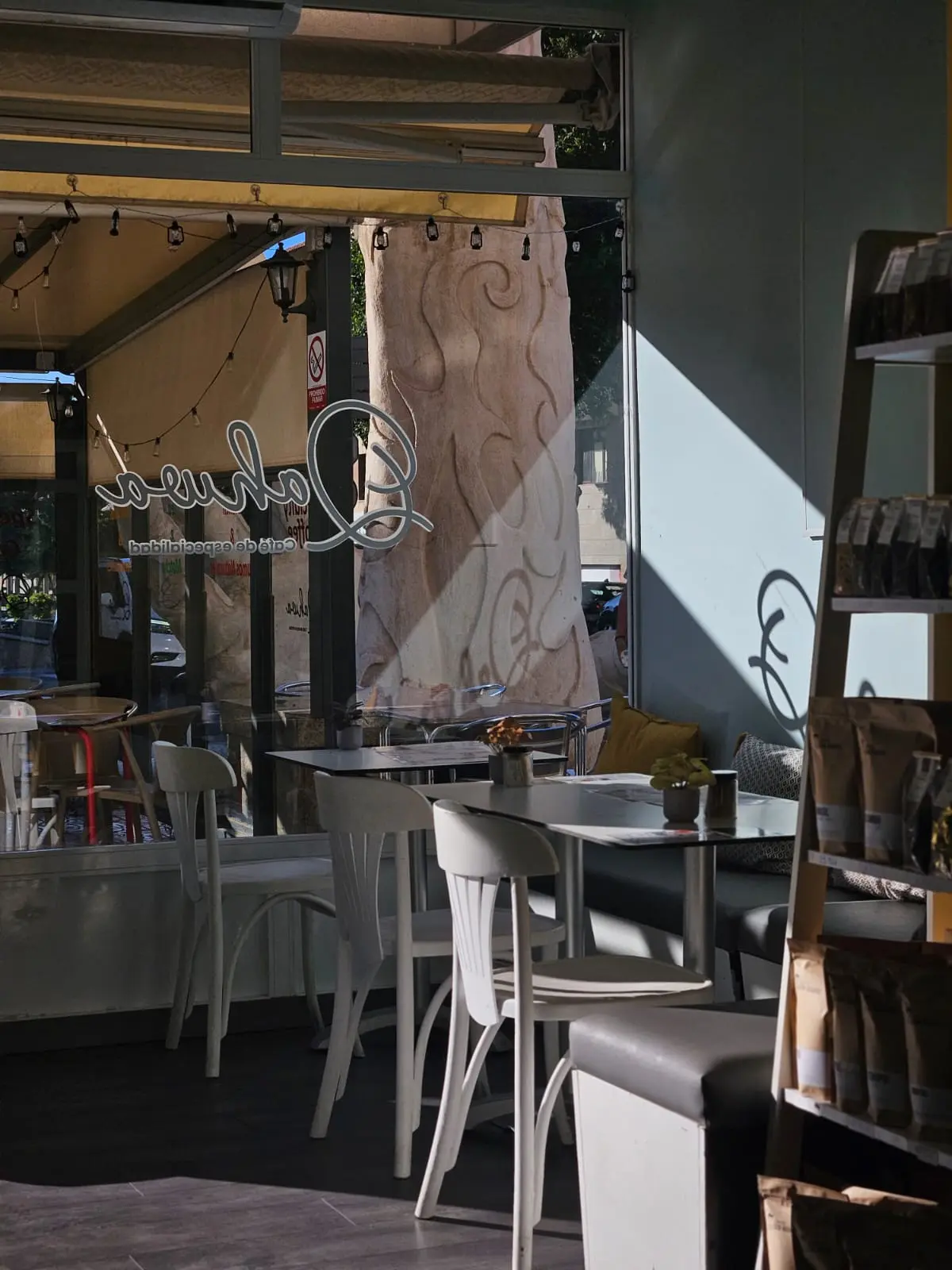 Interior con mesas, sillas blancas y mural artístico